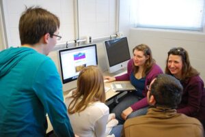 A group of students and Tracey Holloway sit around a computer